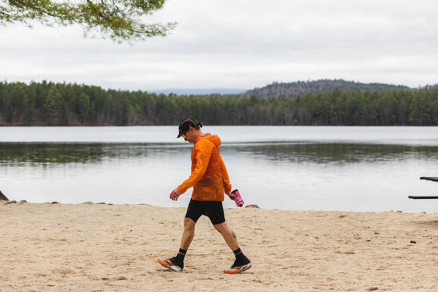 A runner crossing the beach along the lake