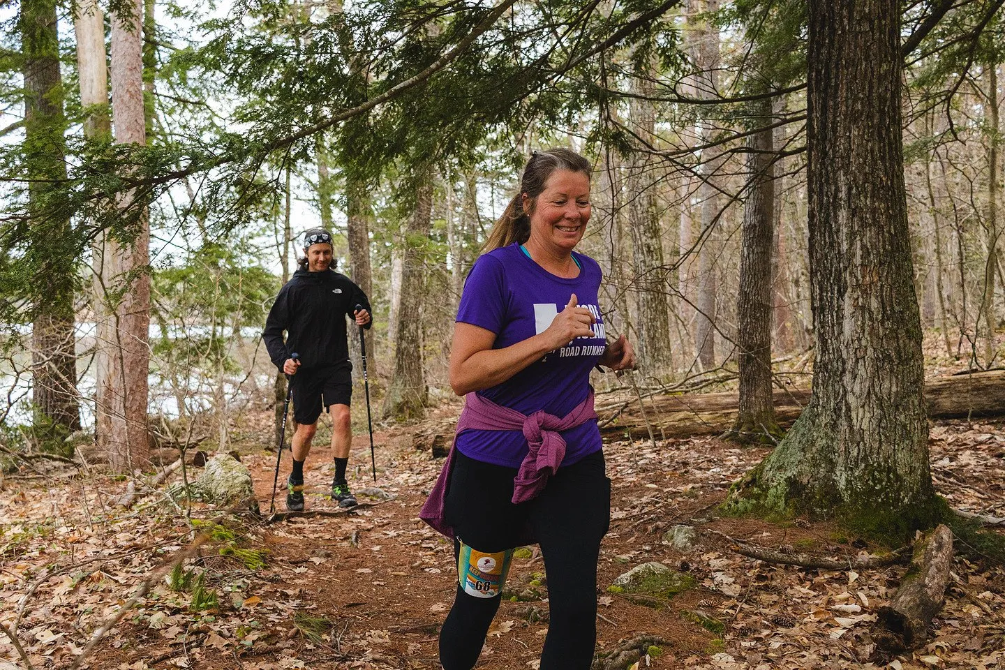 A runner smiling through the pines above the lake