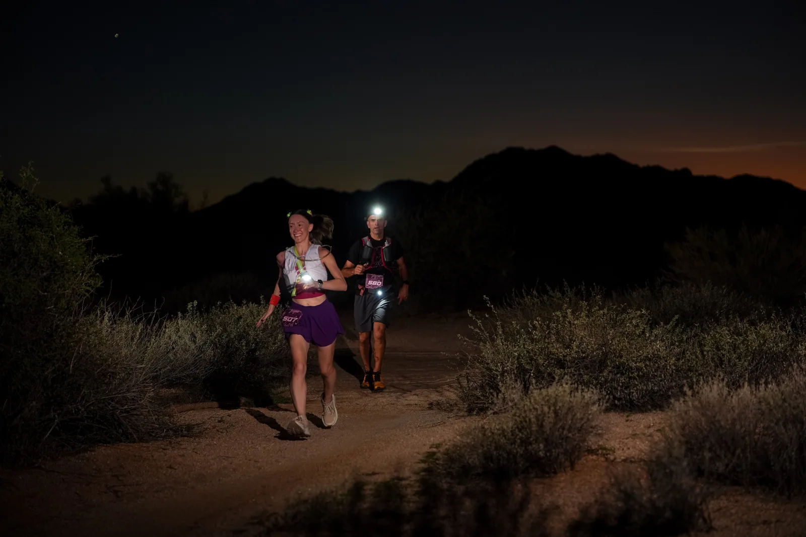 Runners at dusk and by headlamp at the Javelina Jangover Night Runs in McDowell Mountain Regional Park