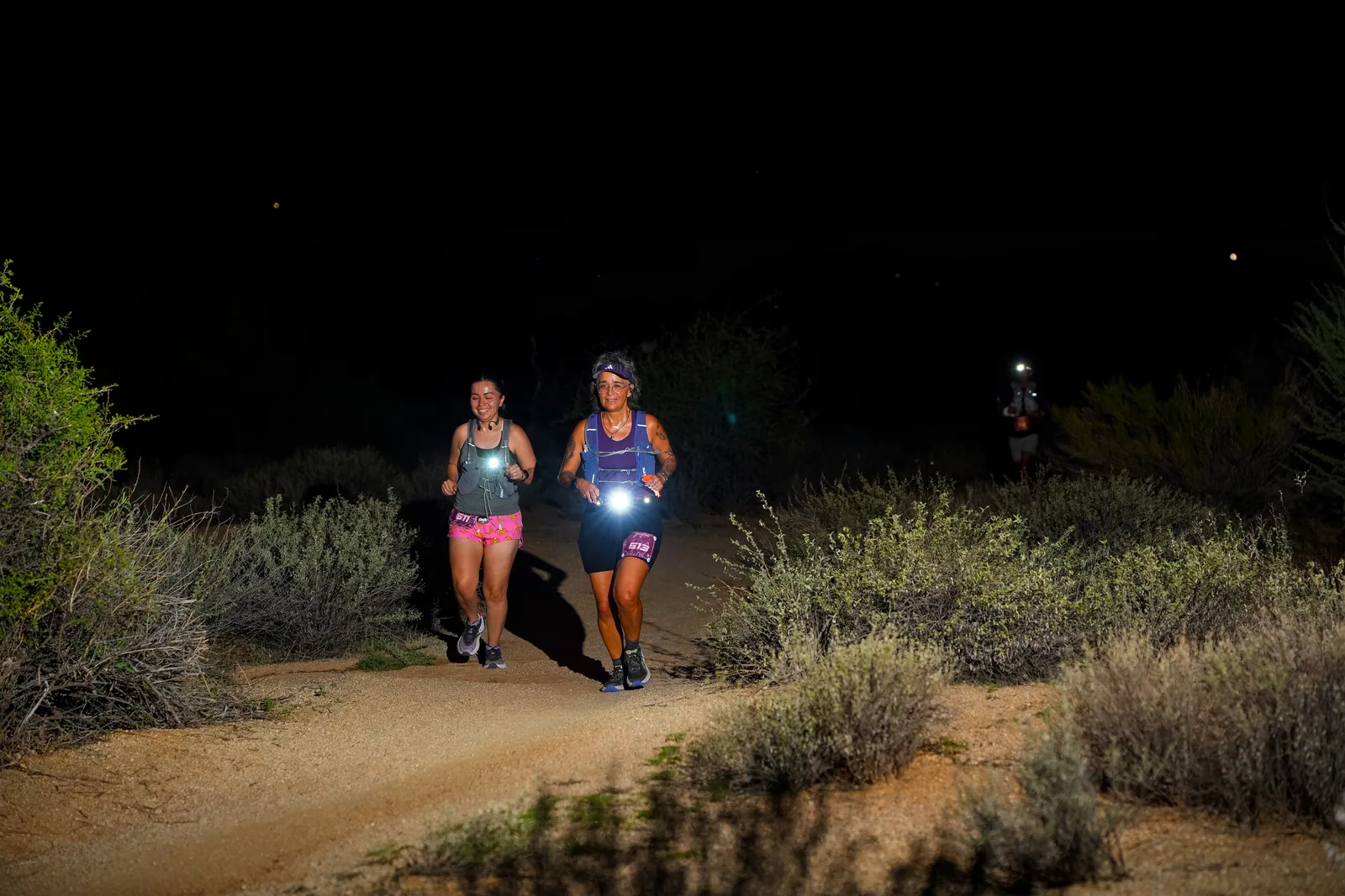Runners at dusk and by headlamp at the Javelina Jangover Night Runs in McDowell Mountain Regional Park