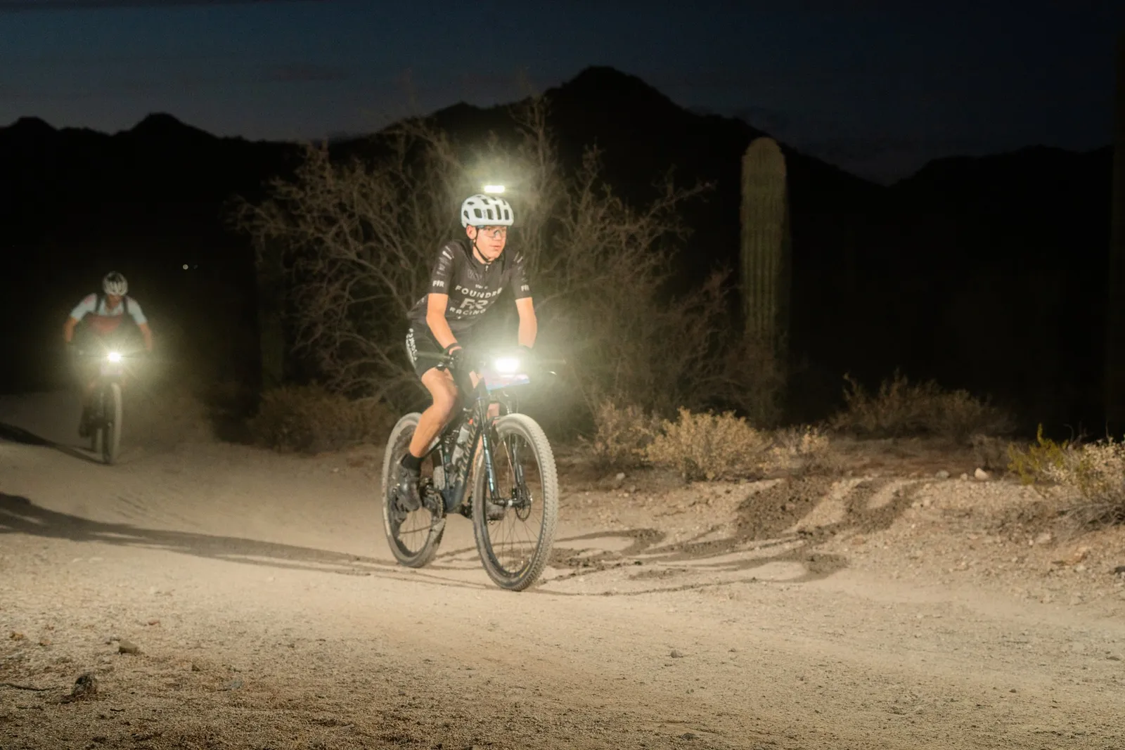 Rider by bike light among the saguaros at the Sinister Night Rides in San Tan Mountain Regional Park
