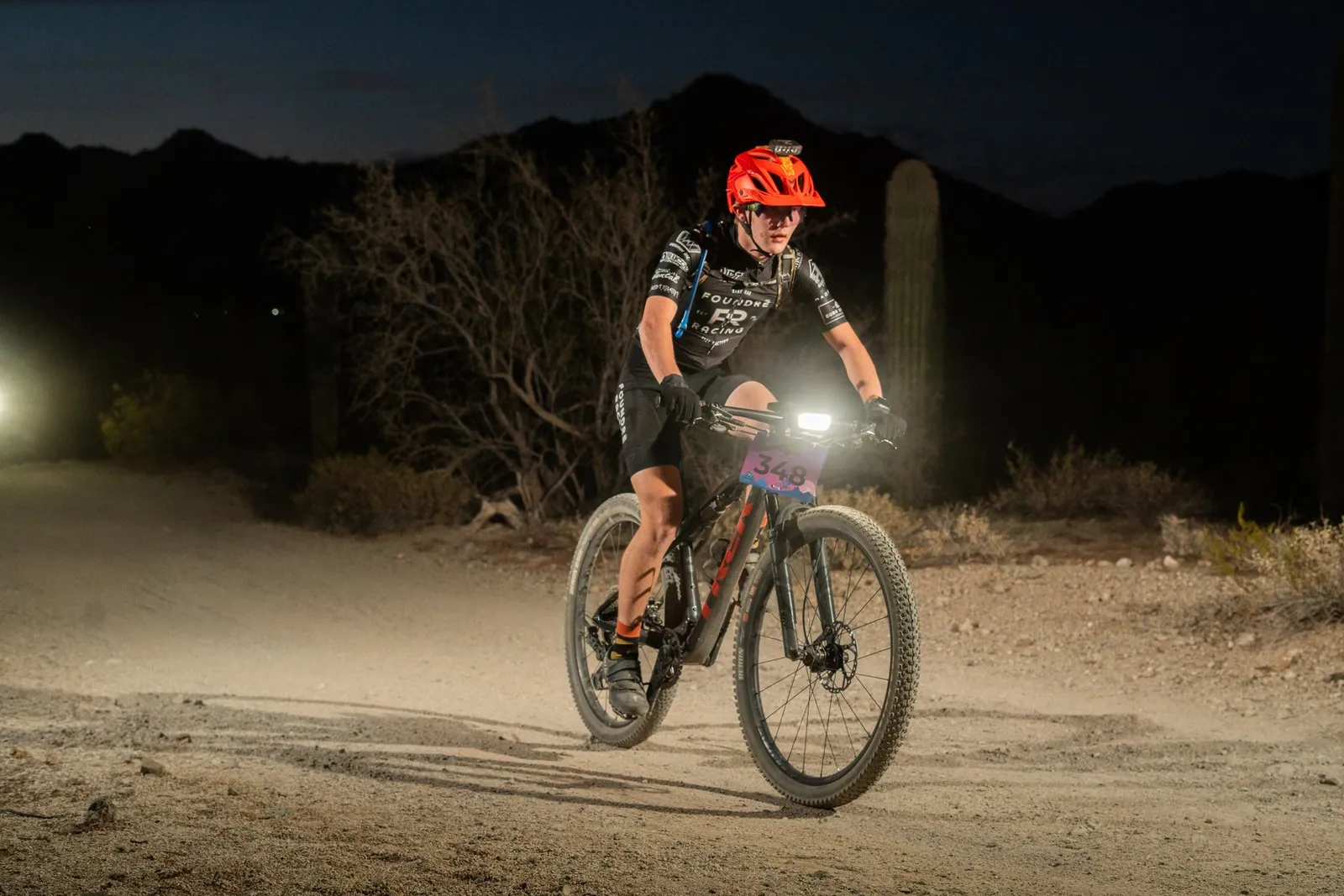 Rider by bike light among the saguaros at the Sinister Night Rides in San Tan Mountain Regional Park