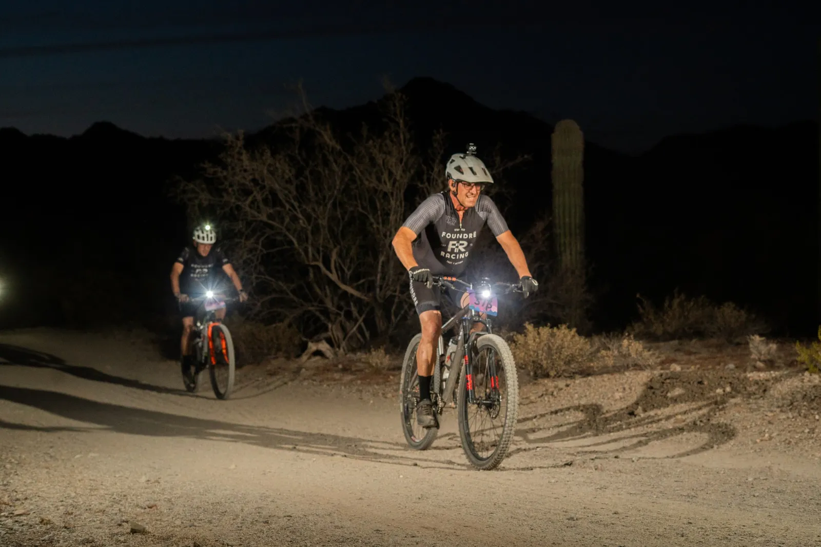 Rider by bike light among the saguaros at the Sinister Night Rides in San Tan Mountain Regional Park