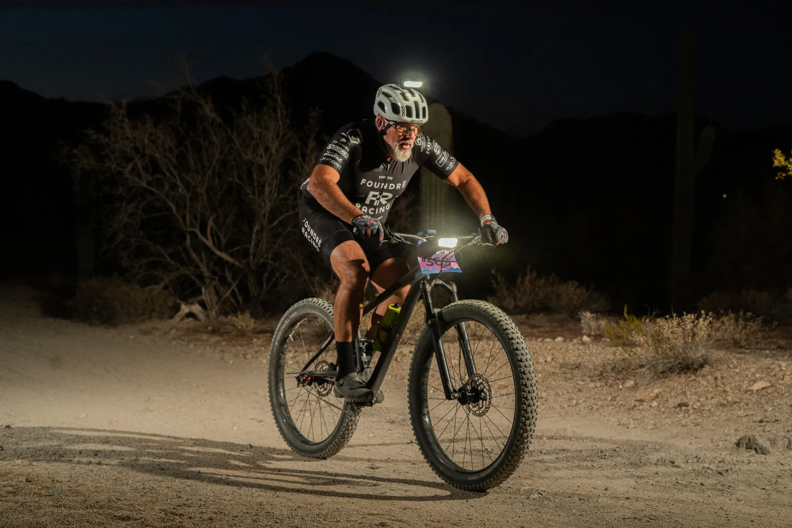 Rider by bike light among the saguaros at the Sinister Night Rides in San Tan Mountain Regional Park