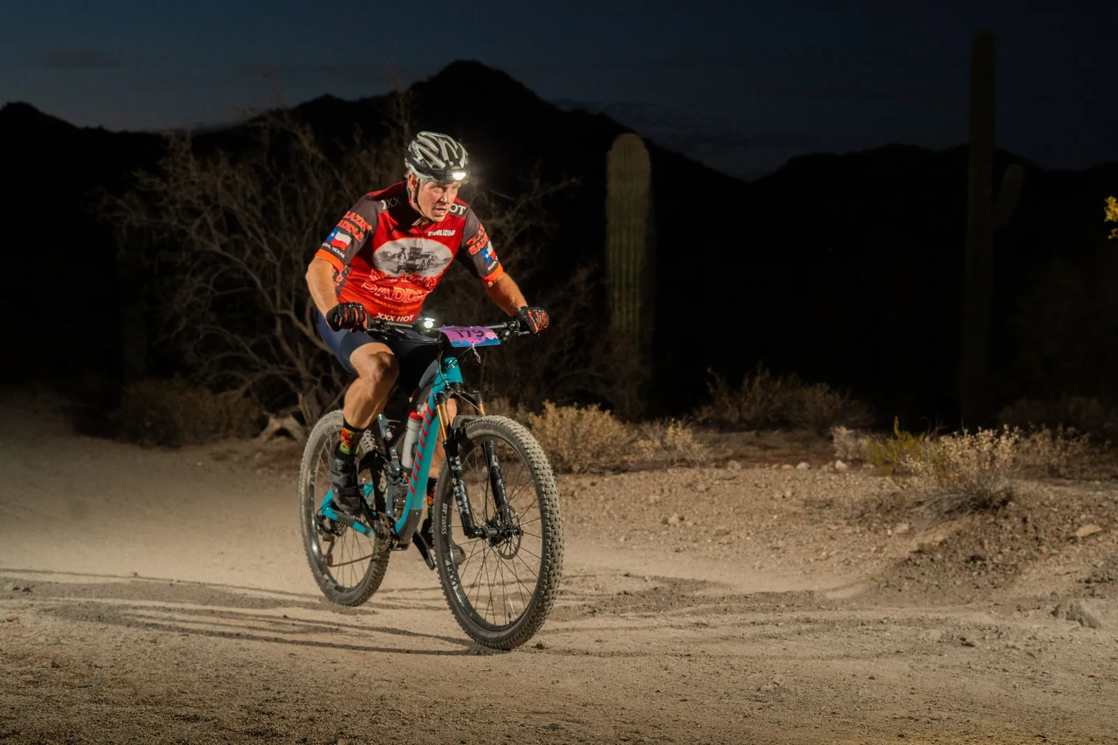Rider by bike light among the saguaros at the Sinister Night Rides in San Tan Mountain Regional Park