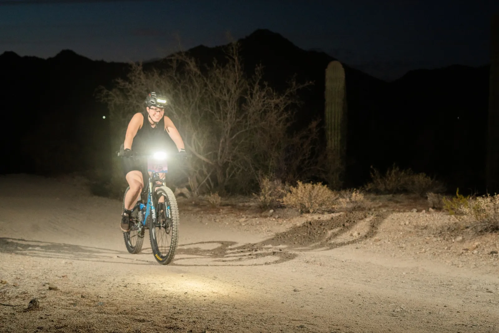 Rider by bike light among the saguaros at the Sinister Night Rides in San Tan Mountain Regional Park