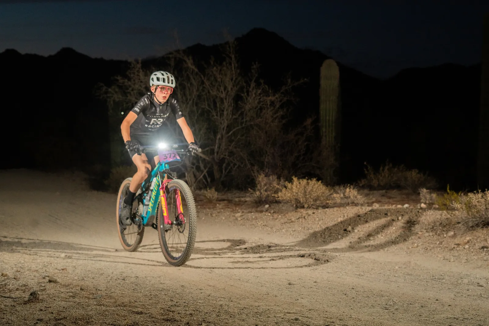 Rider by bike light among the saguaros at the Sinister Night Rides in San Tan Mountain Regional Park