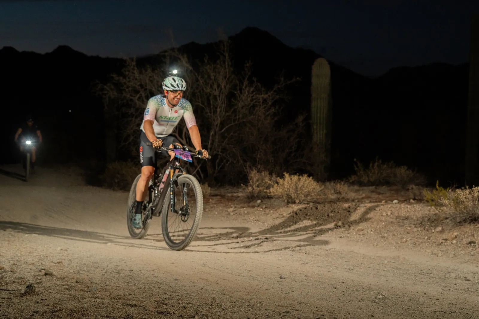 Rider by bike light among the saguaros at the Sinister Night Rides in San Tan Mountain Regional Park