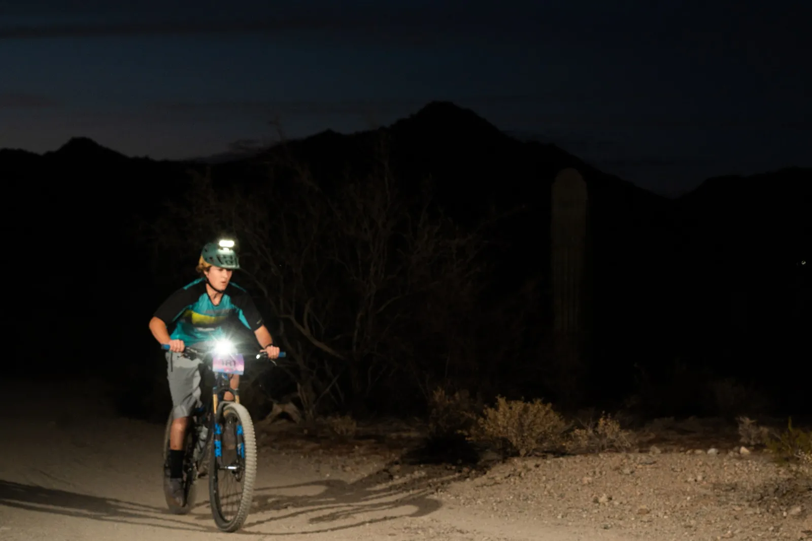 Rider by bike light among the saguaros at the Sinister Night Rides in San Tan Mountain Regional Park
