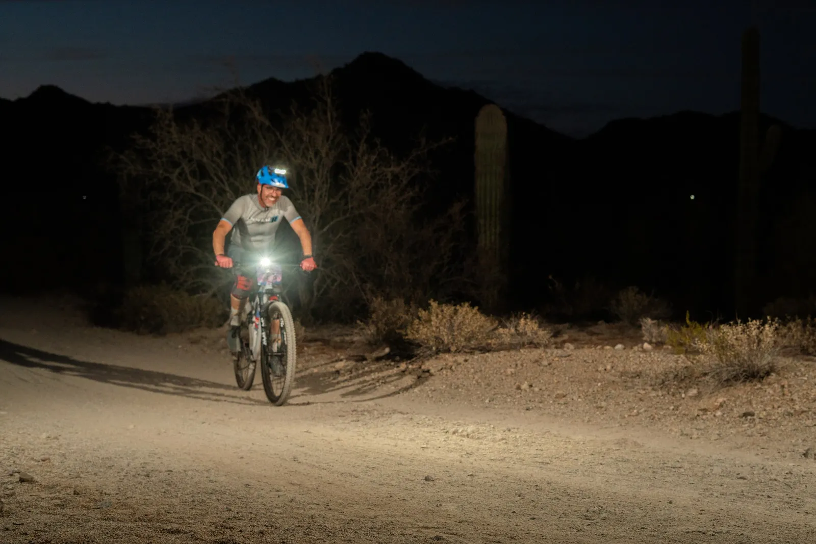 Rider by bike light among the saguaros at the Sinister Night Rides in San Tan Mountain Regional Park