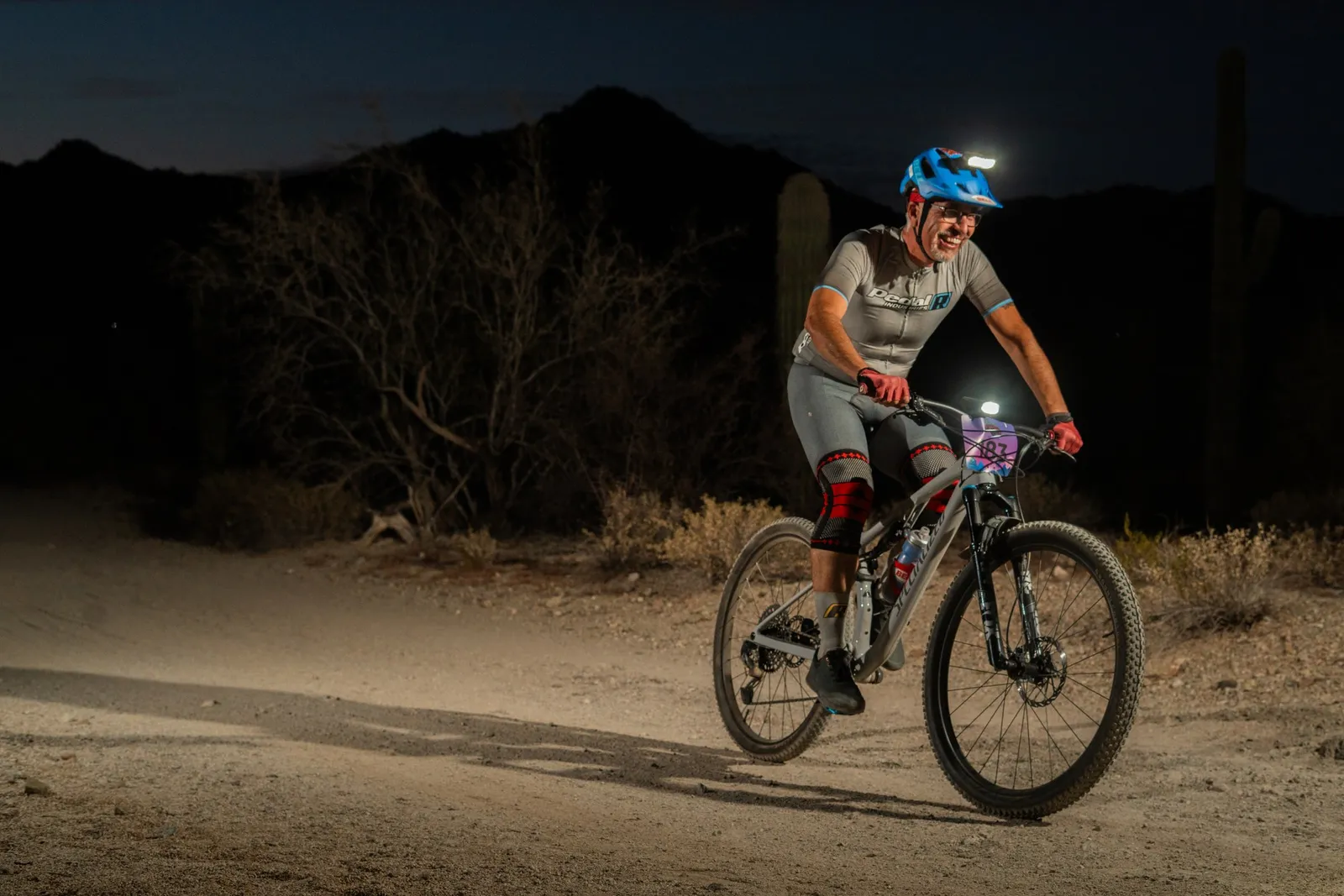Rider by bike light among the saguaros at the Sinister Night Rides in San Tan Mountain Regional Park