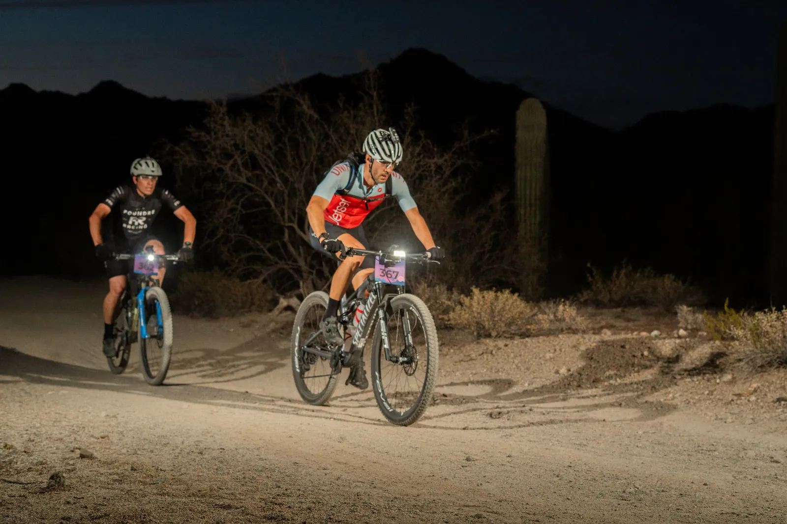 Rider by bike light among the saguaros at the Sinister Night Rides in San Tan Mountain Regional Park