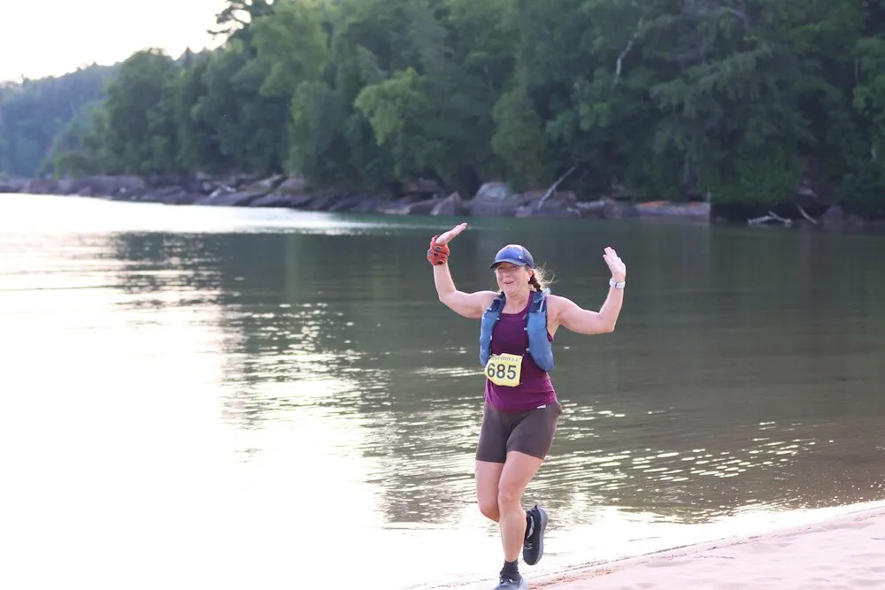 A runner celebrating on a Lake Superior beach
