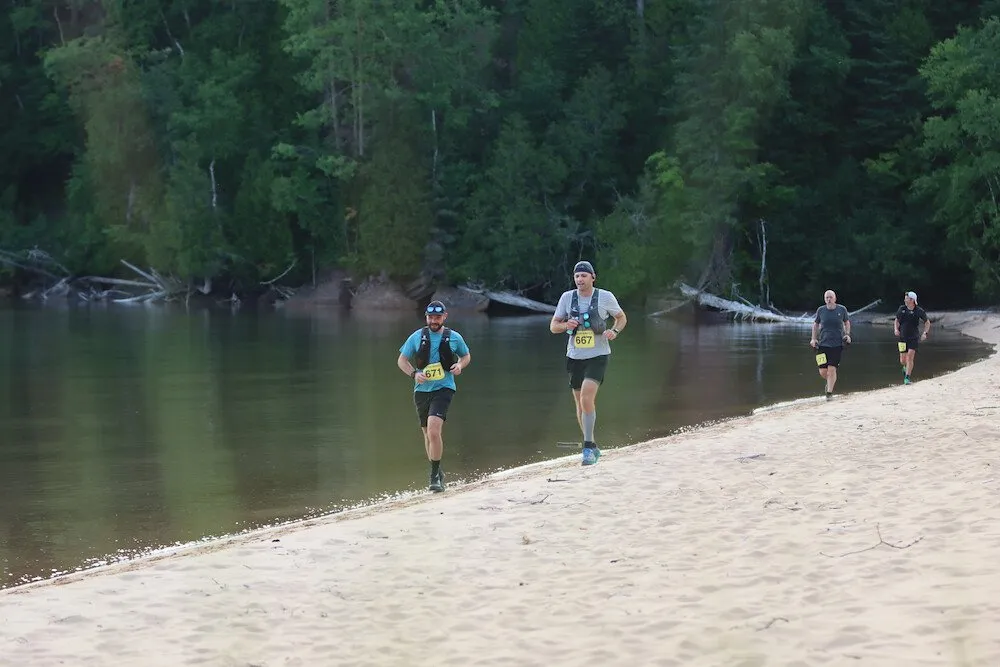 Runners crossing a sand beach
