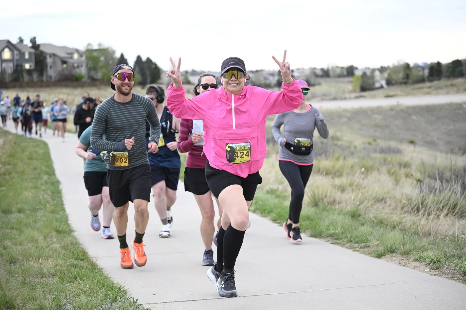 A runner throwing up peace signs on the trail