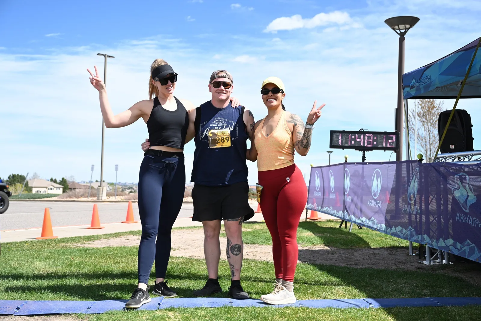 Three finishers celebrating at the arch