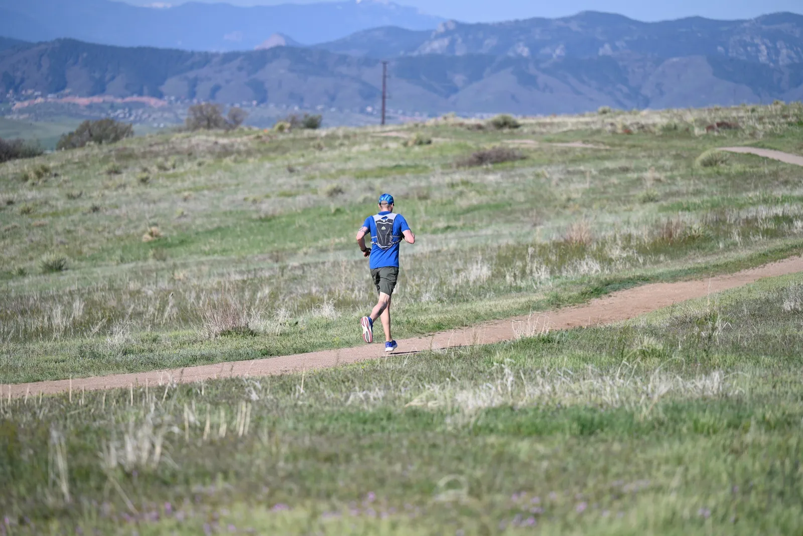 A runner crossing open grassland below the mountains