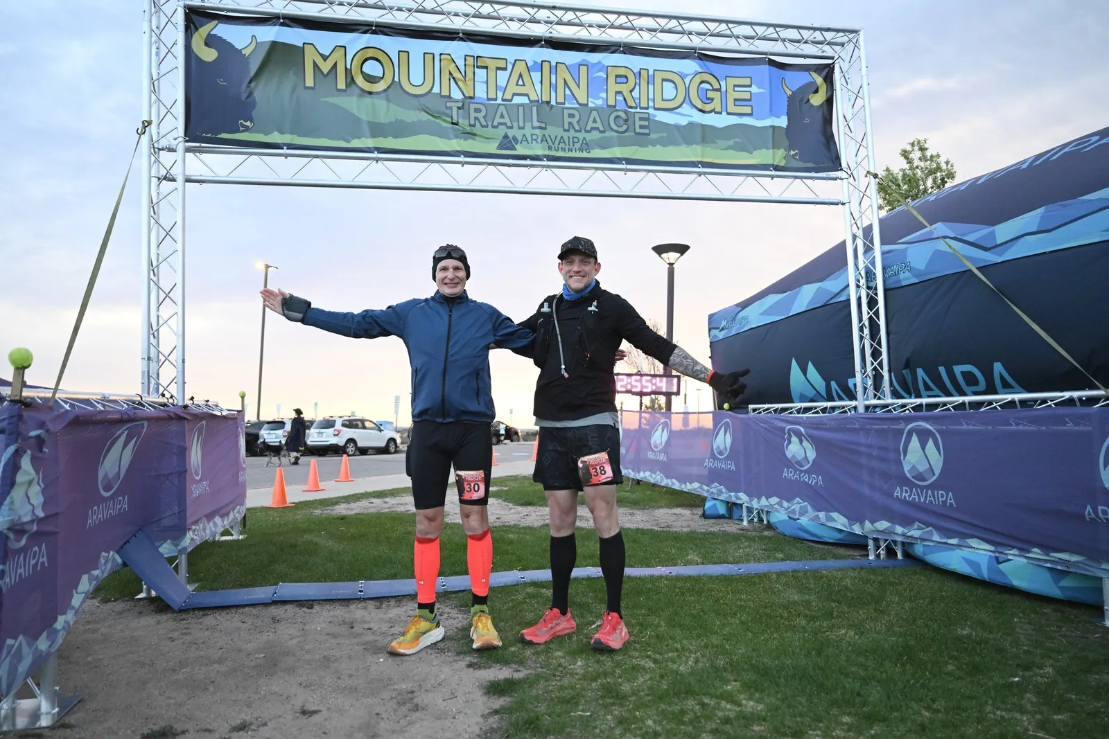 Two runners posing under the Mountain Ridge arch