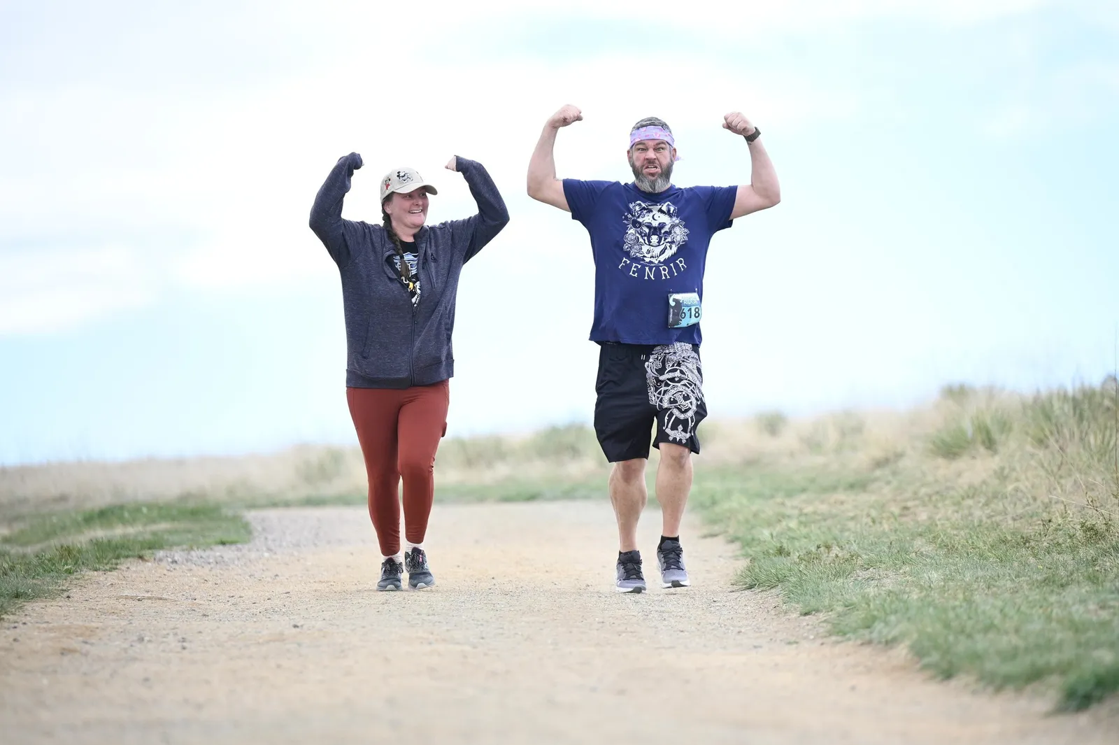 Two runners flexing on the trail