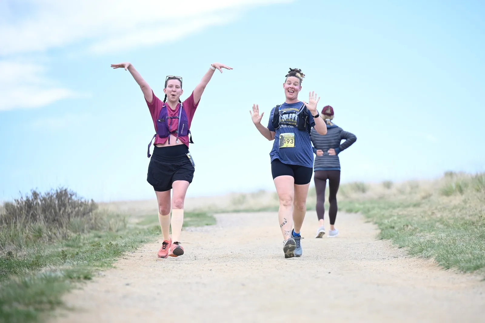 A runner with arms raised on the open trail