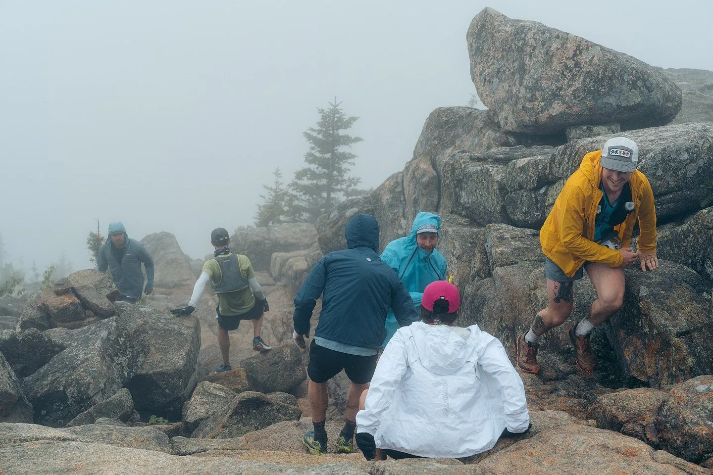 A crowd of runners scrambling granite near the top