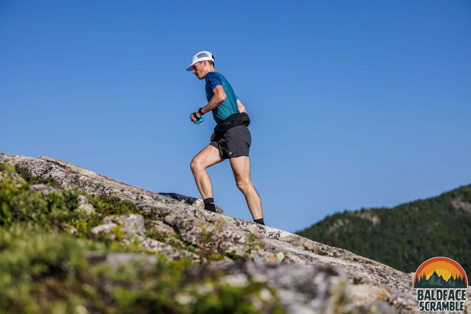 Runner climbing bare granite against a blue sky