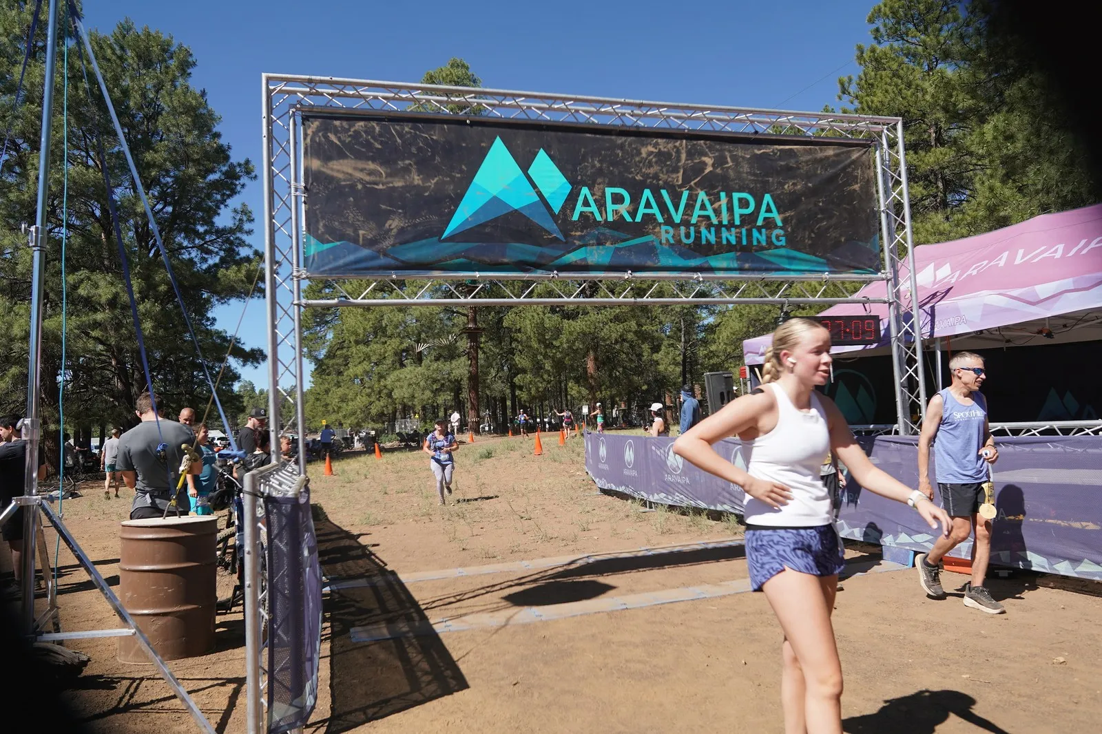 Two runners finishing at the Big Pine Trail Runs finish line in the Flagstaff ponderosa pines
