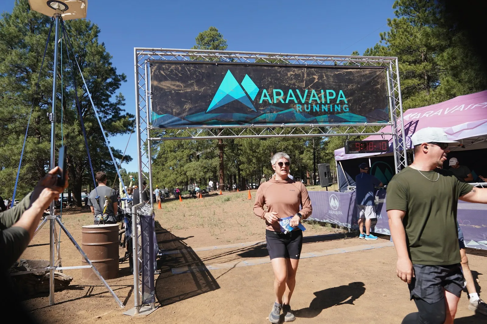 A finisher walking through the Big Pine Trail Runs finish line in the Flagstaff ponderosa pines