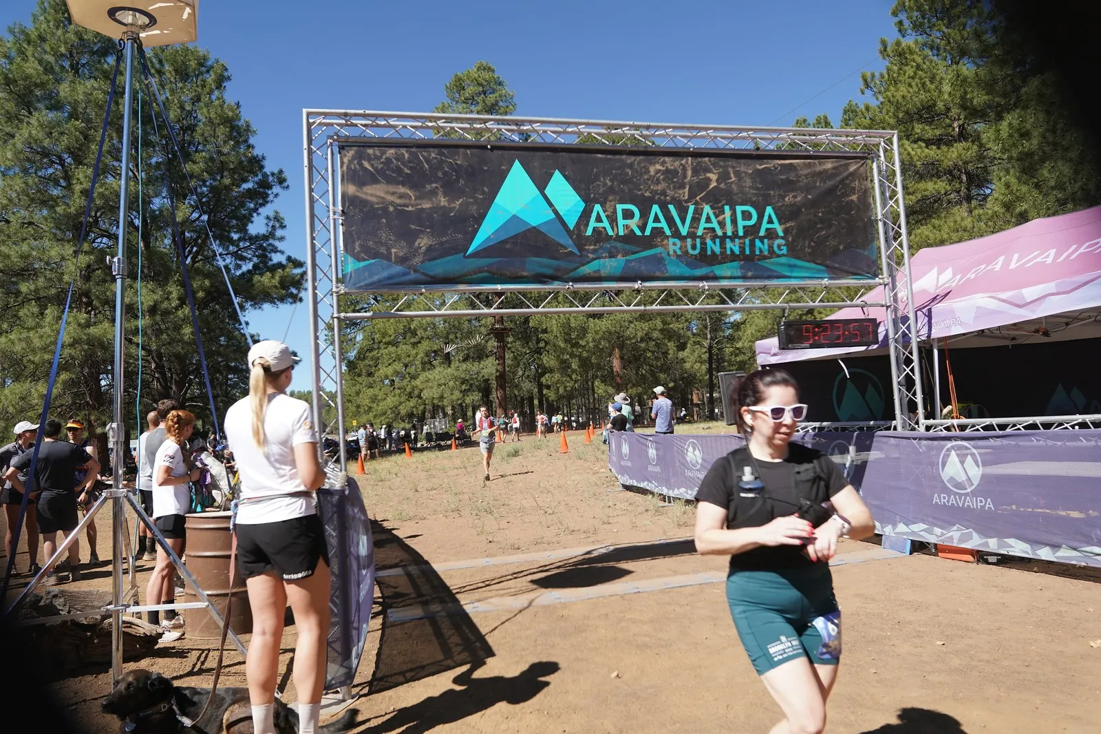 A runner smiling at the Big Pine Trail Runs finish line in the Flagstaff ponderosa pines