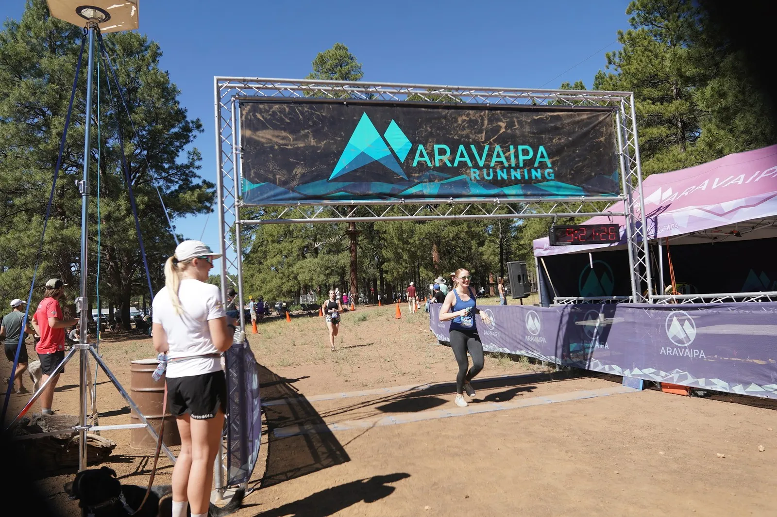 A runner in grey at the Big Pine Trail Runs finish line in the Flagstaff ponderosa pines