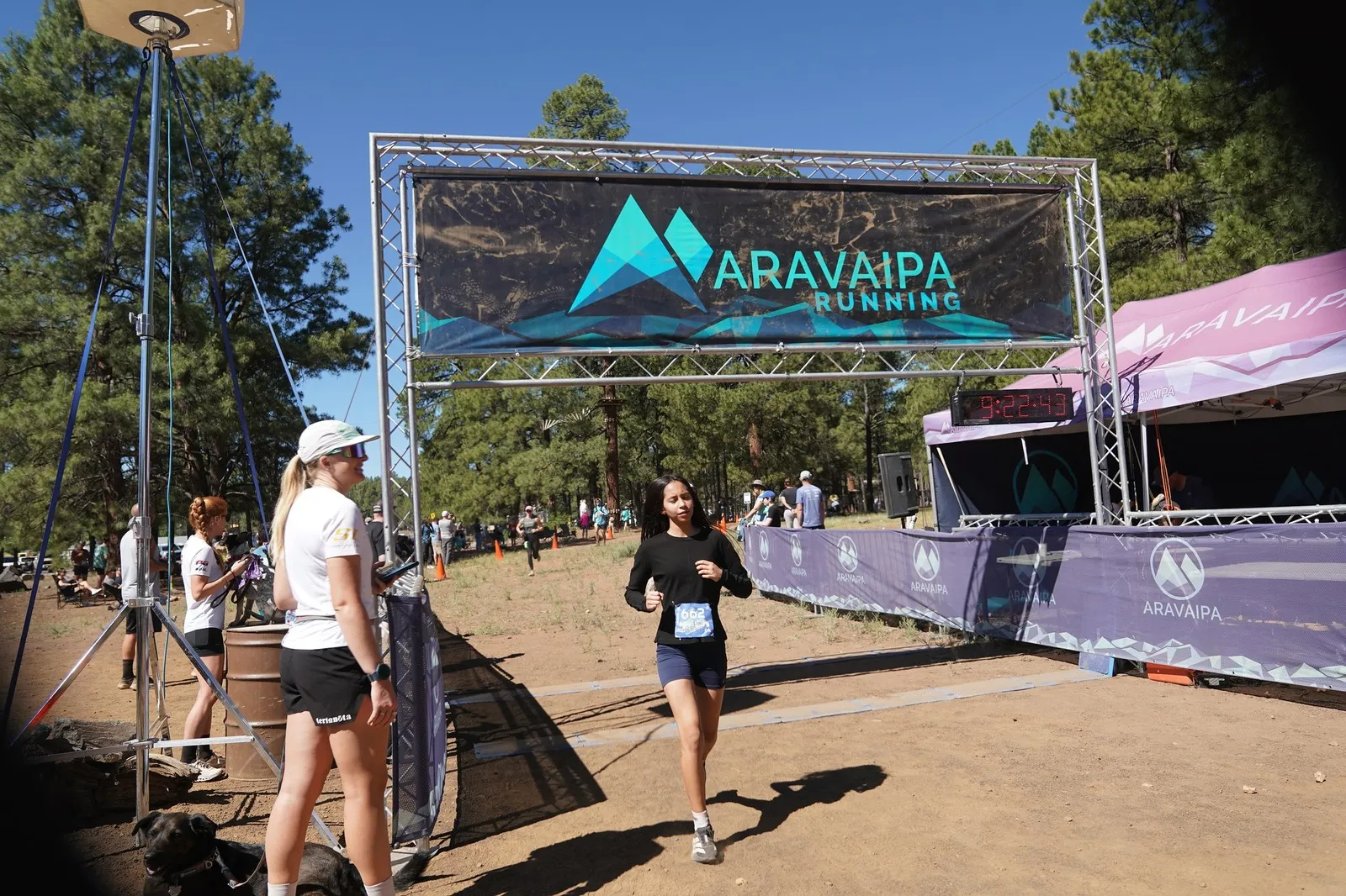 A runner in black at the Big Pine Trail Runs finish line in the Flagstaff ponderosa pines
