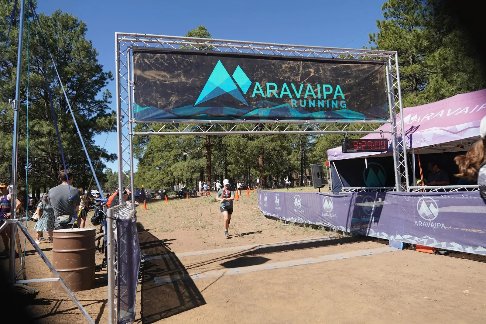 A runner in white at the Big Pine Trail Runs finish line in the Flagstaff ponderosa pines