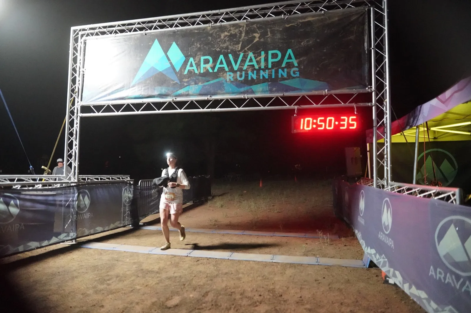 A runner with a headlamp at the Blackout Night Runs finish line in the Flagstaff pines