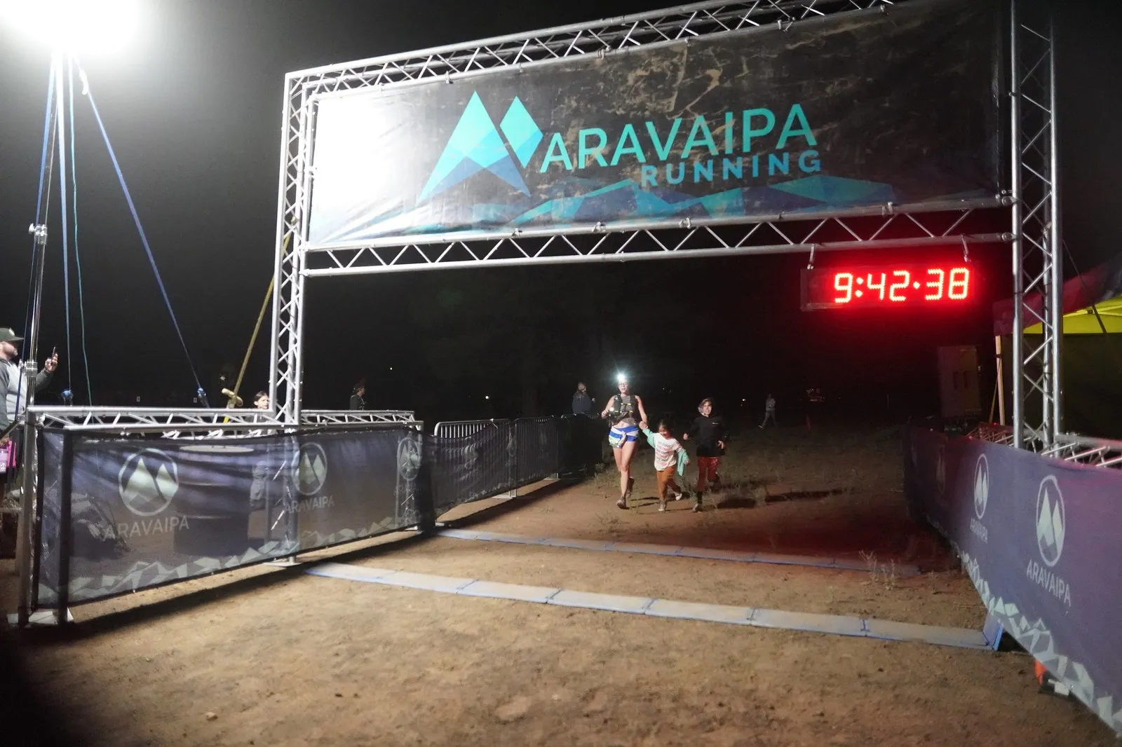 A family finishing together at the Blackout Night Runs finish line in the Flagstaff pines