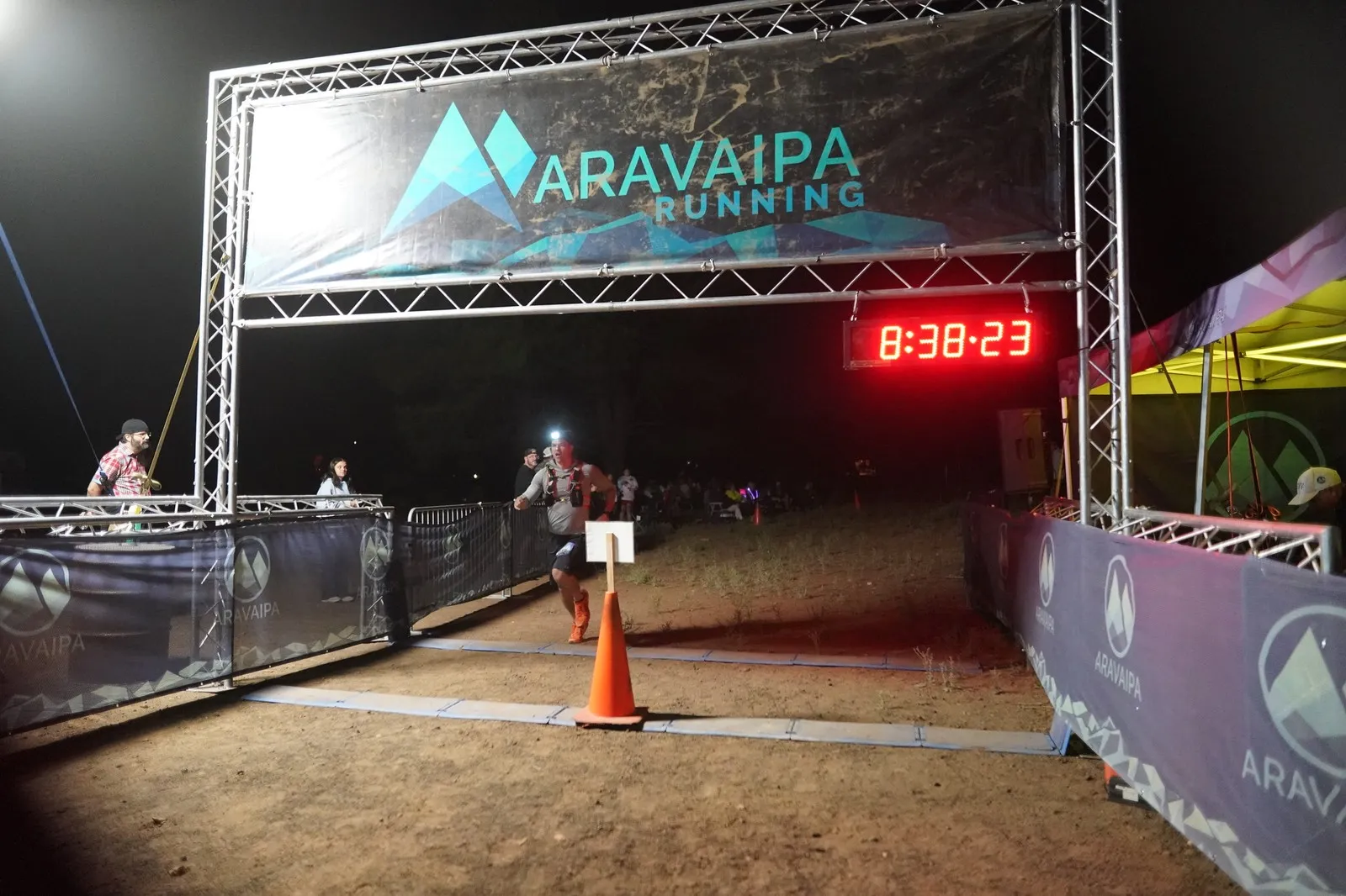 A runner crossing the Blackout Night Runs finish line in the Flagstaff pines