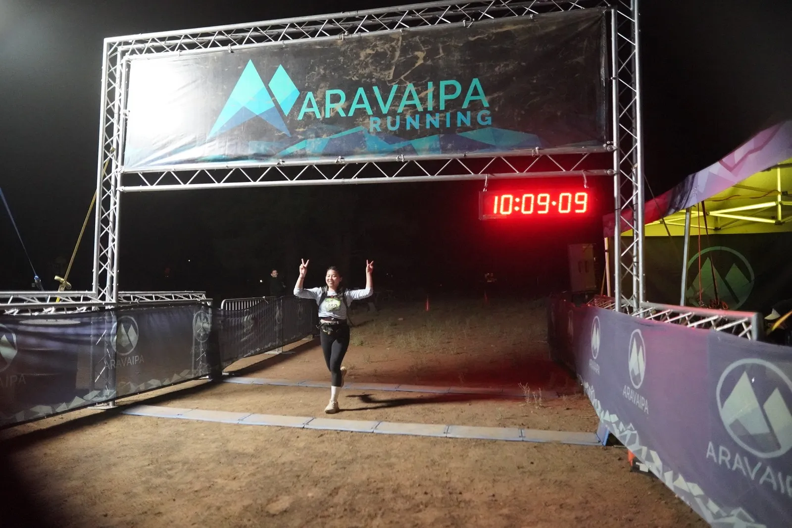 A runner celebrating at the Blackout Night Runs finish line in the Flagstaff pines