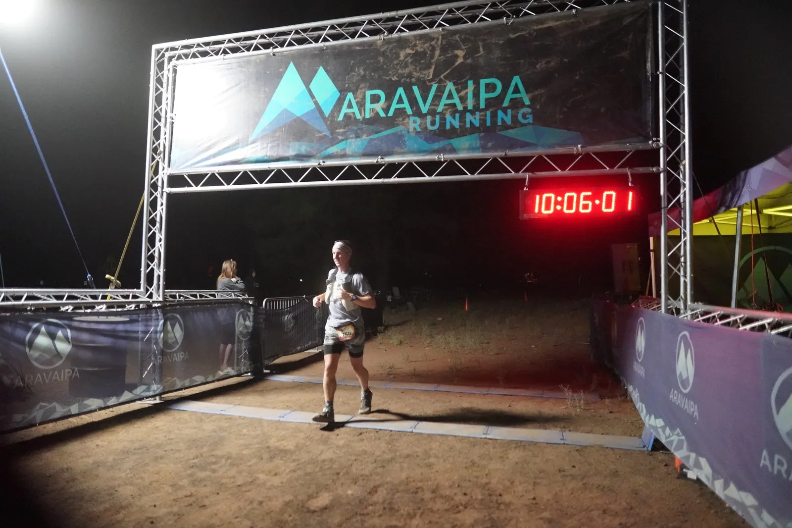 A runner in grey at the Blackout Night Runs finish line in the Flagstaff pines