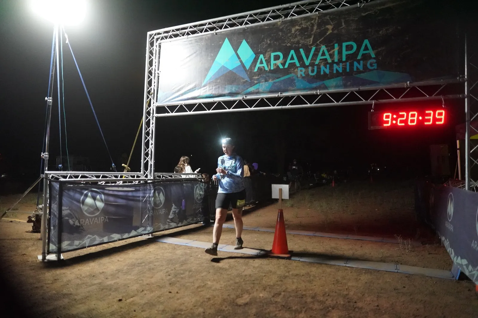 A runner in a headlamp at the Blackout Night Runs finish line in the Flagstaff pines