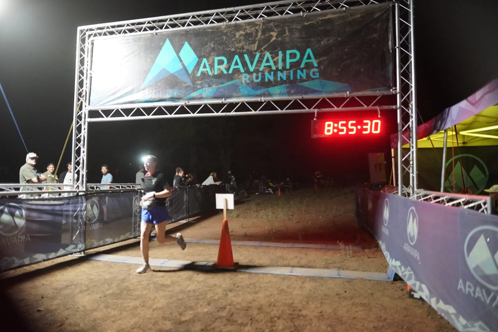 A runner crossing the Blackout Night Runs finish line in the Flagstaff pines