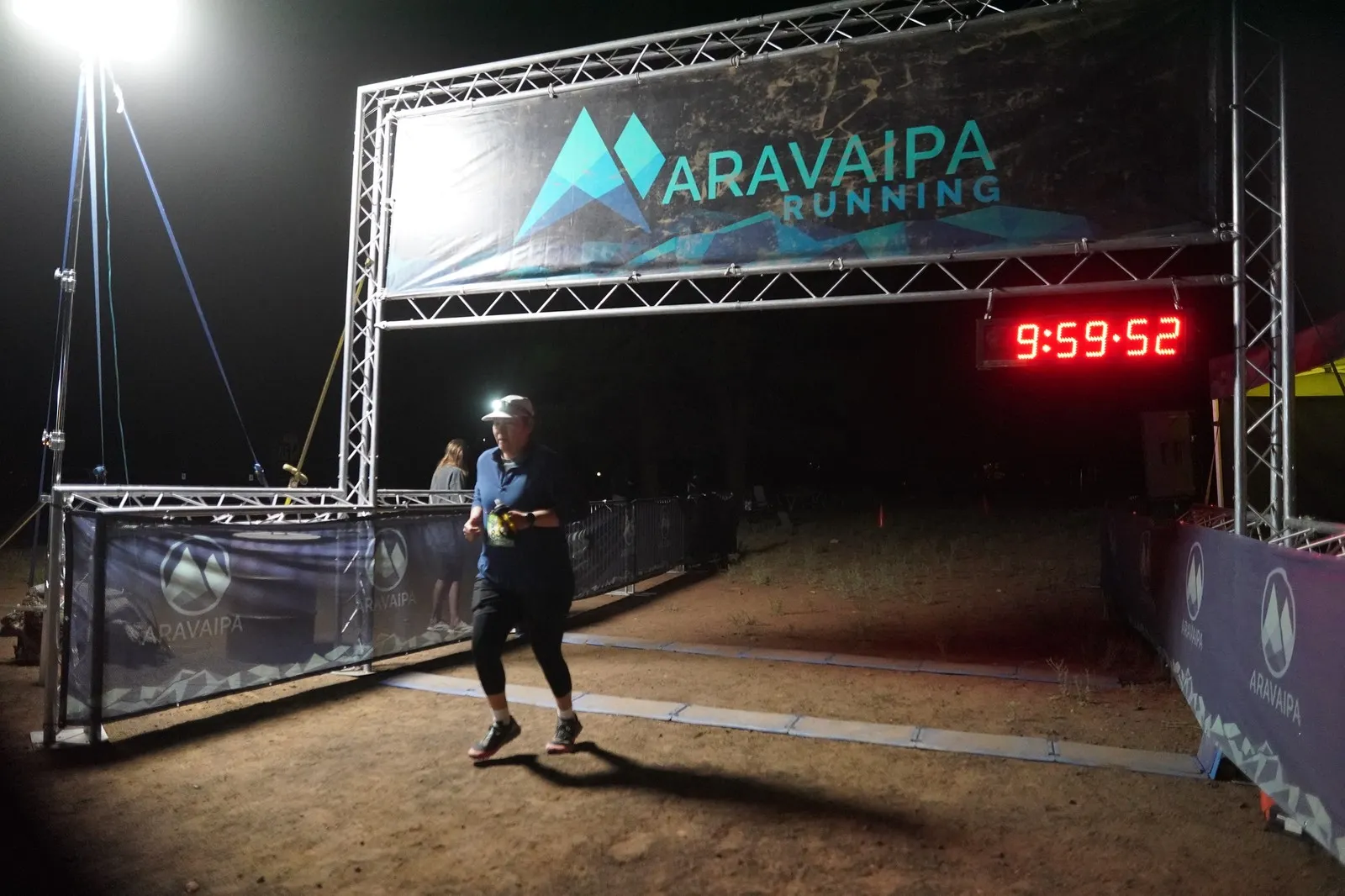 A runner close to the camera at the Blackout Night Runs finish line in the Flagstaff pines