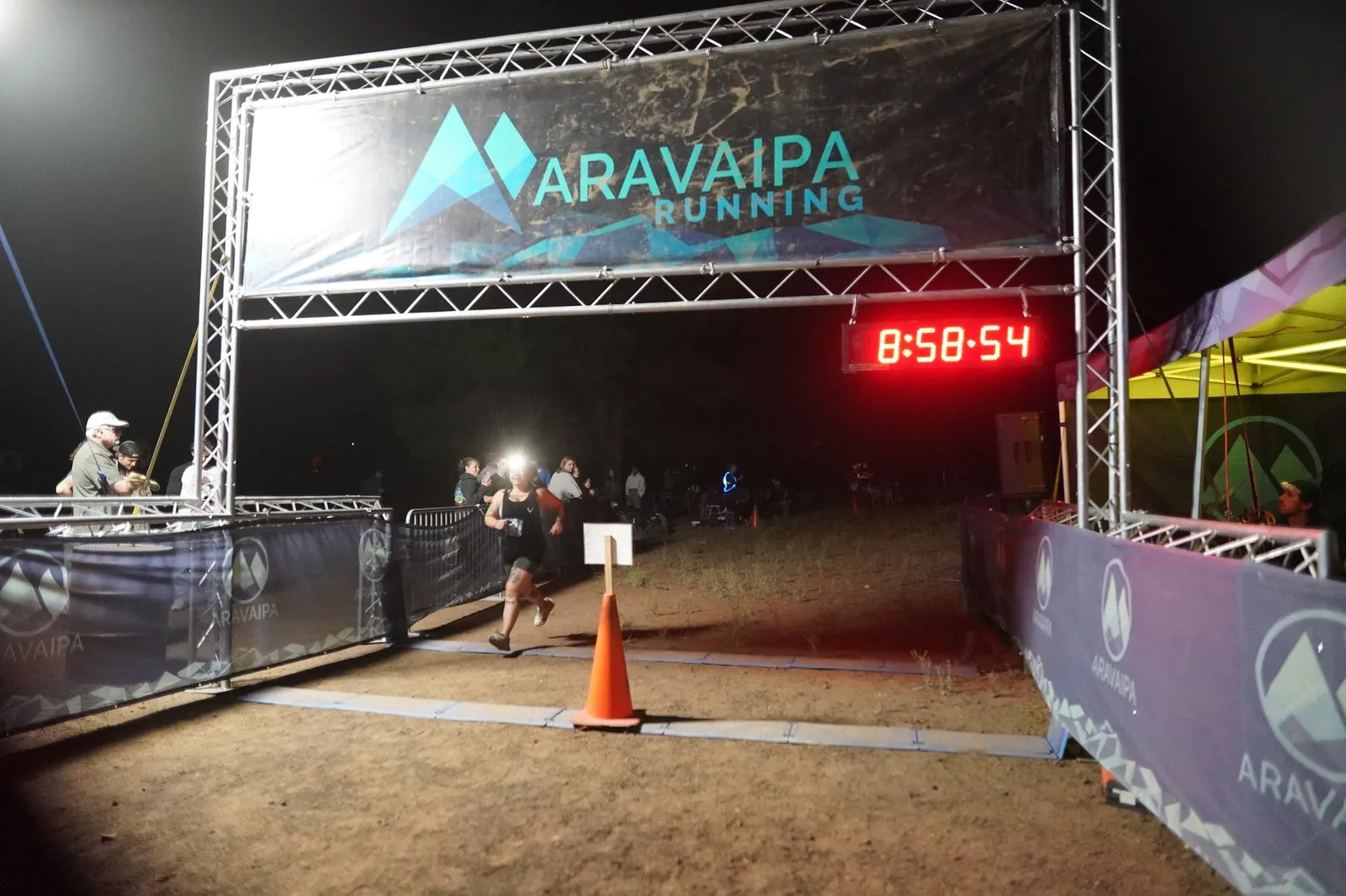 A runner reaching the Blackout Night Runs finish line in the Flagstaff pines