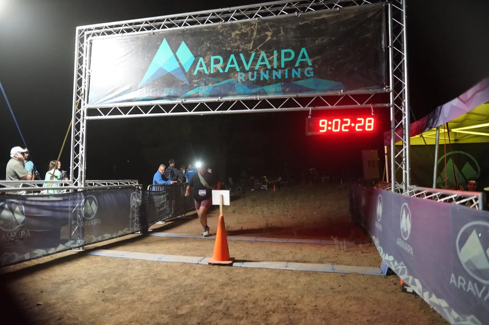 A runner in orange shorts at the Blackout Night Runs finish line in the Flagstaff pines