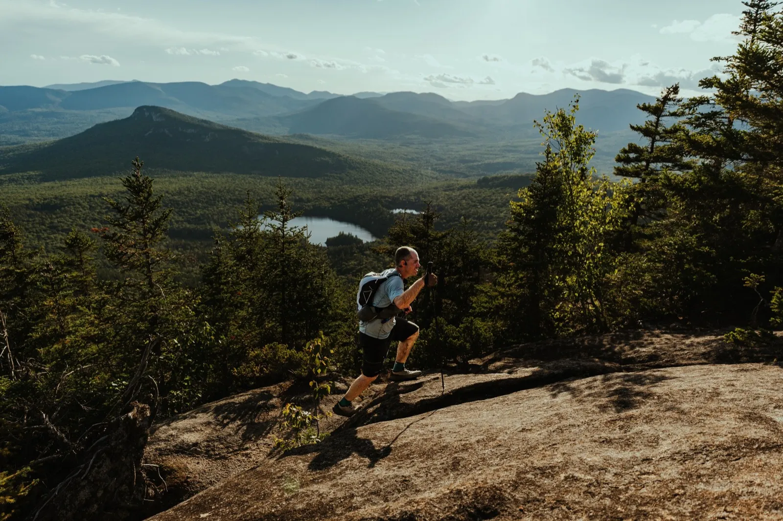 A runner climbs the granite above a lake as the light turns gold