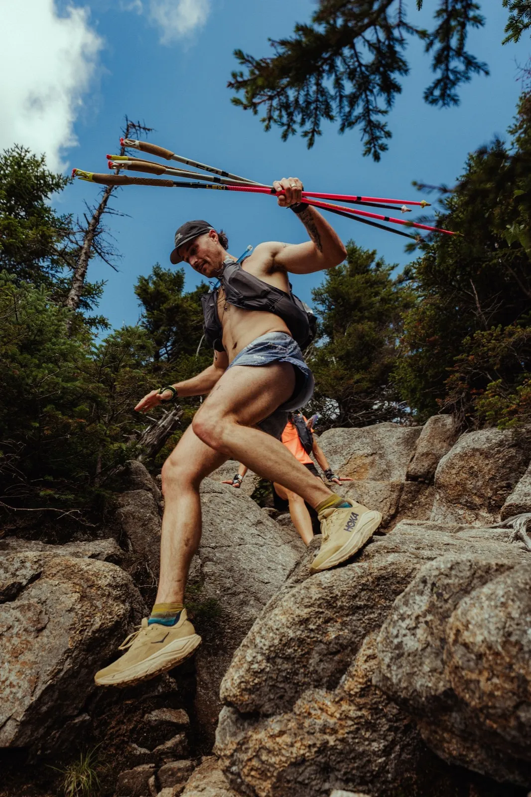 A runner leaps across the boulders with poles held high