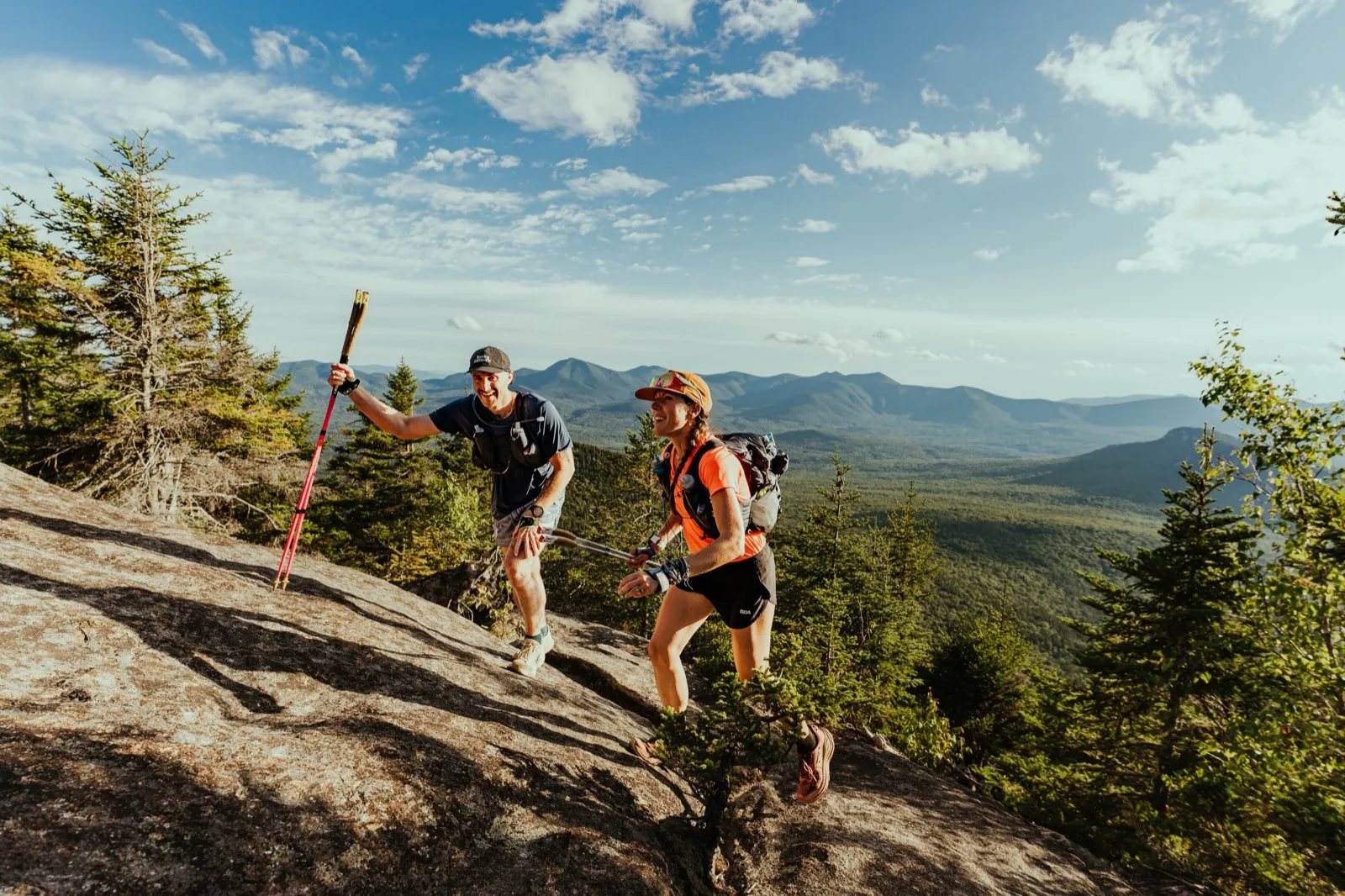 Two runners top out on the open granite with the mountains rolling away behind