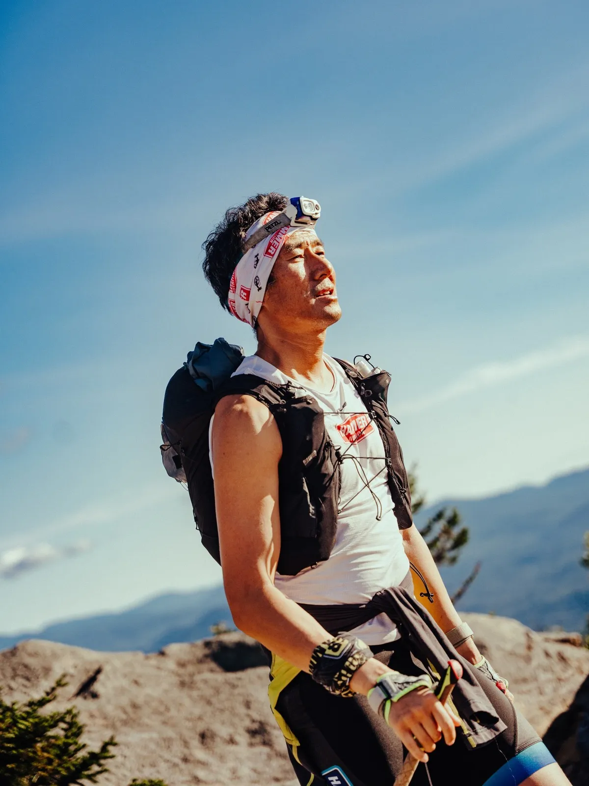 A runner grins up at the sky on the summit rocks