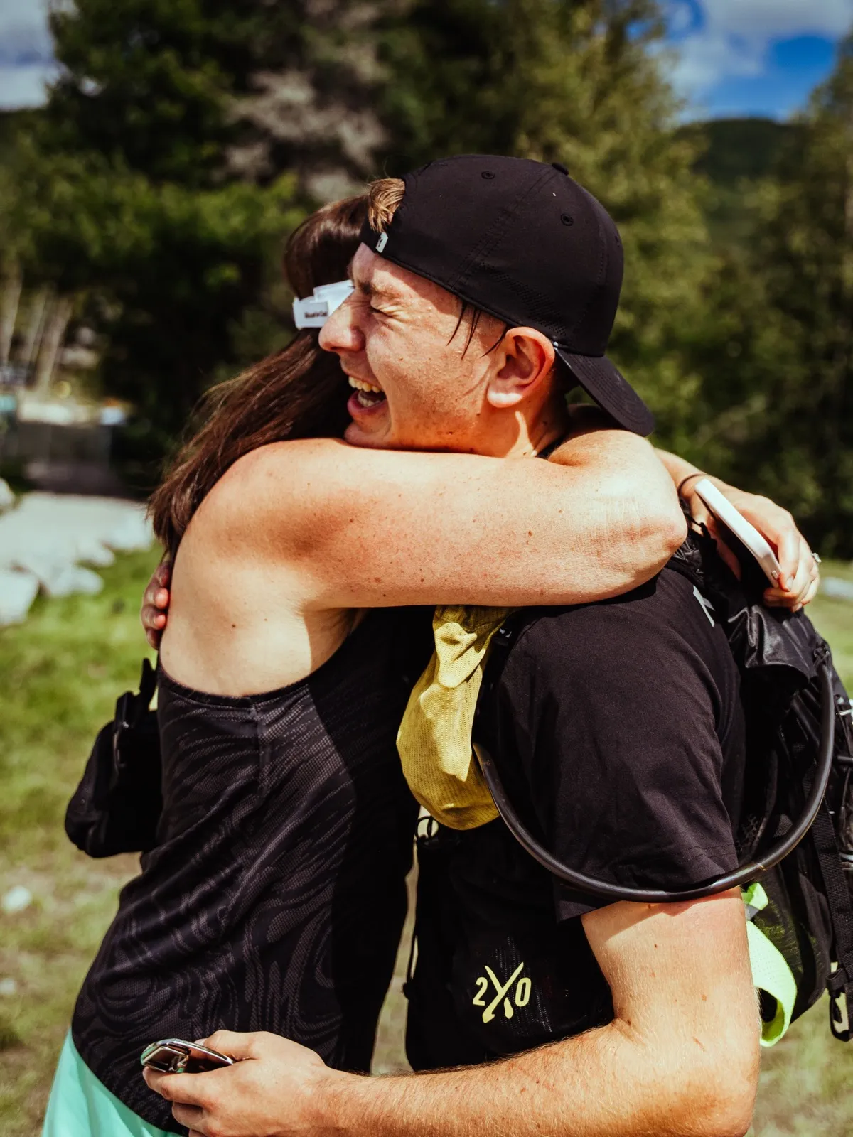 A finisher wraps a friend in a hug at the line