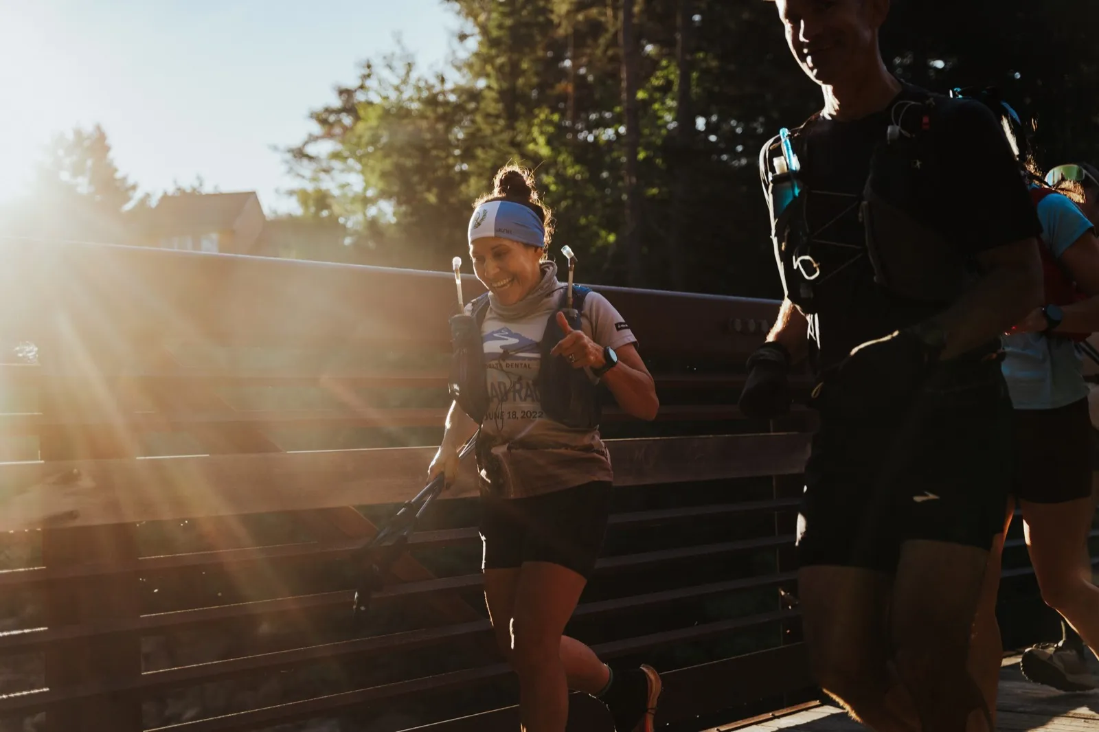 Morning sun breaks through as runners cross the footbridge early in the race