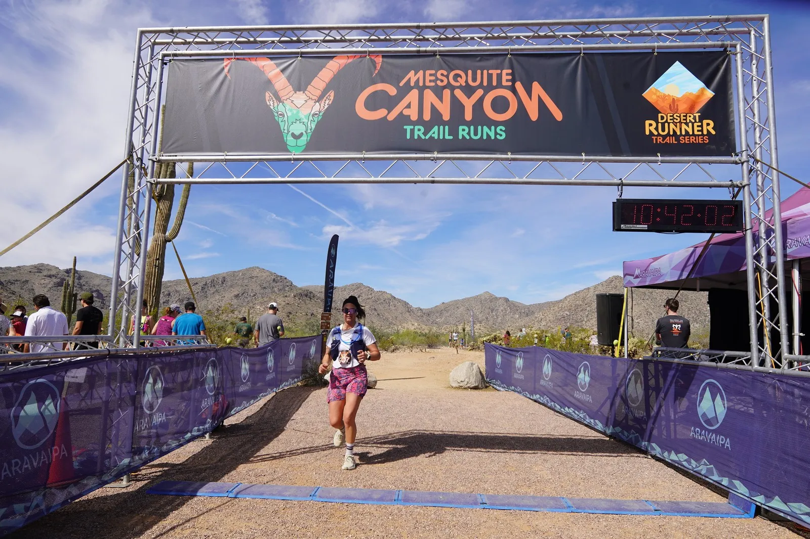 A runner in pink at the Mesquite Canyon Trail Runs finish line, a Sonoran Desert Cup race in White Tank Mountain Regional Park
