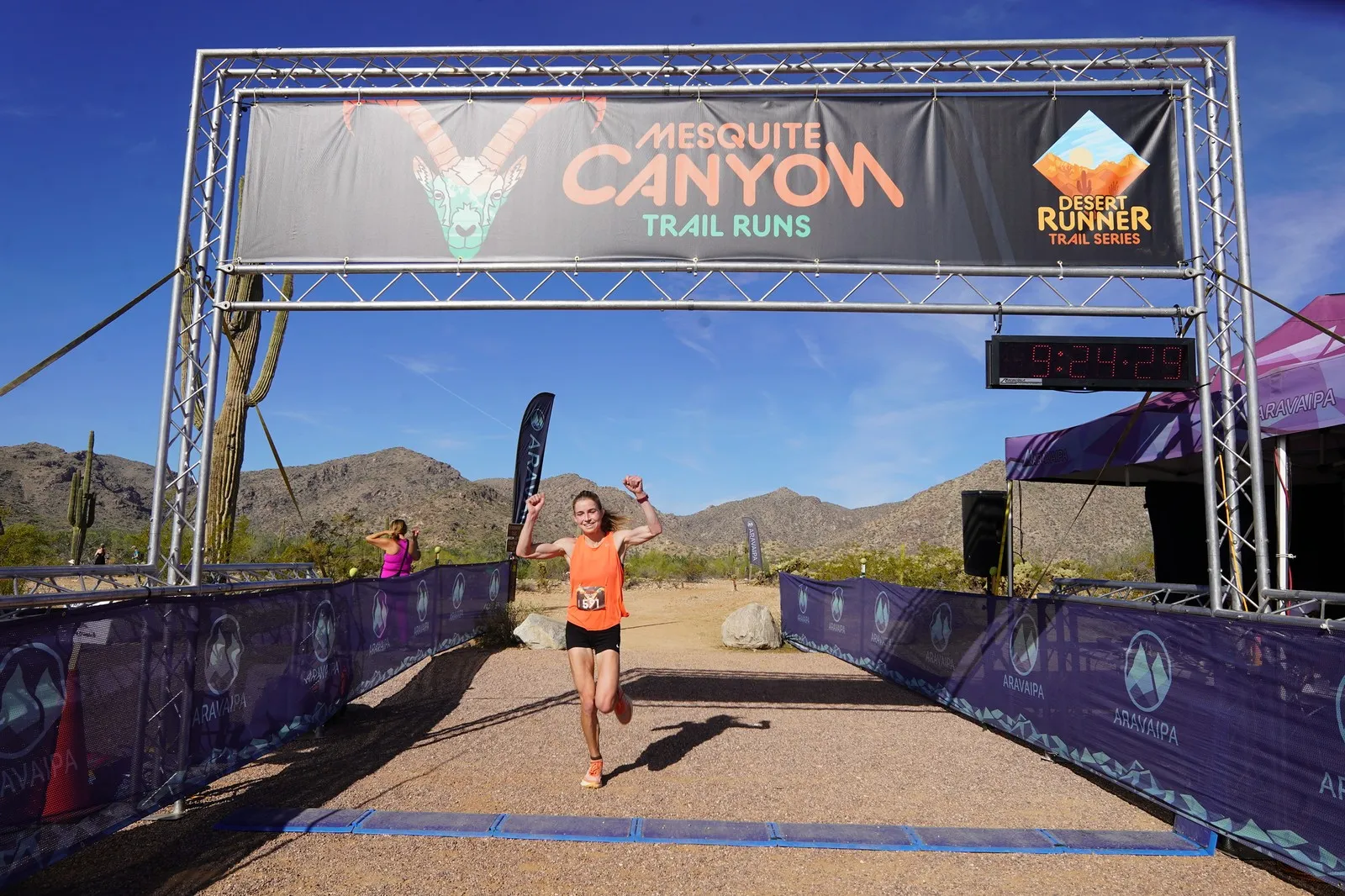 A runner celebrating at the Mesquite Canyon Trail Runs finish line, a Sonoran Desert Cup race in White Tank Mountain Regional Park